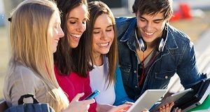 A group of students having fun with smartphones and tablets after class